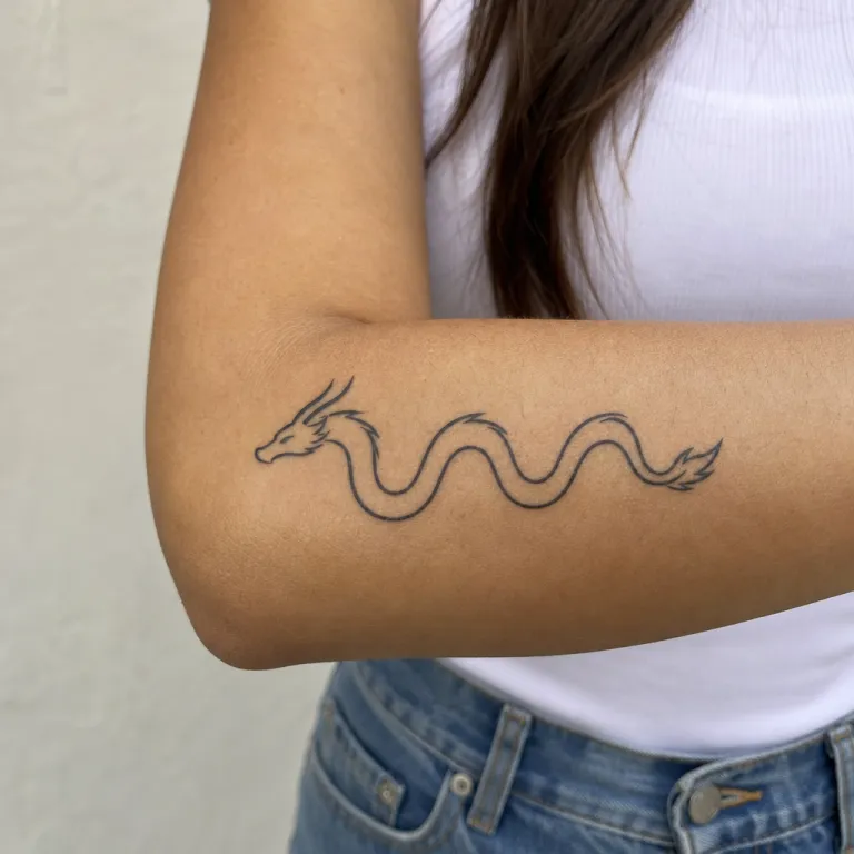 Tatouage dragon minimaliste sur l'avant-bras d'une femme